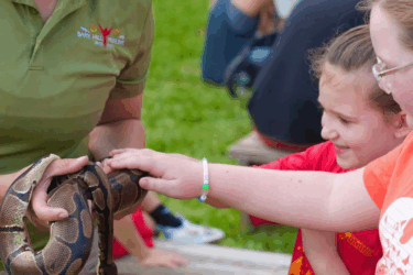 two kids and adult holding snake at magnolia wilds