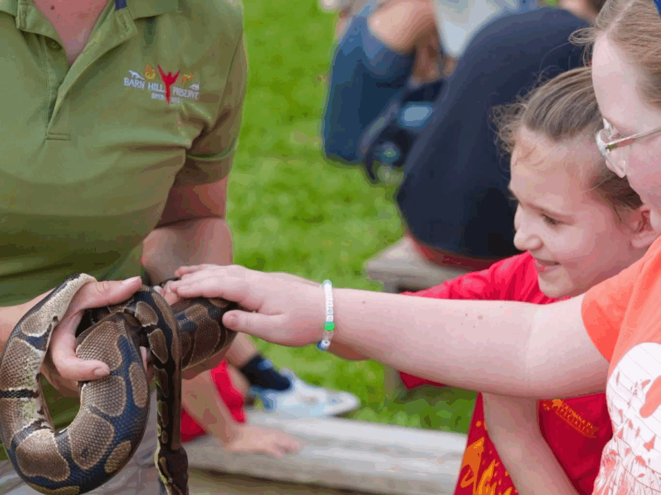 two kids and adult holding snake at magnolia wilds