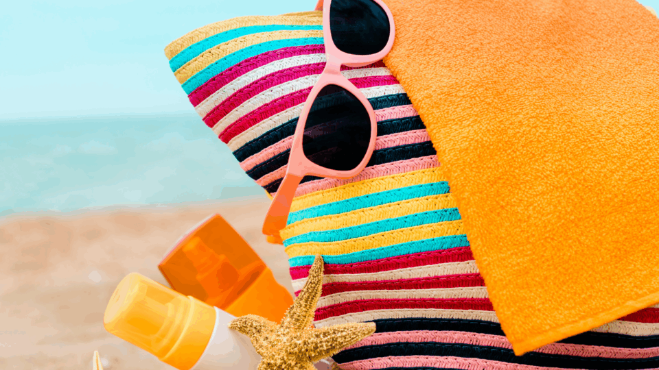 beach bag, sunglasses, and sunscreen on the beach