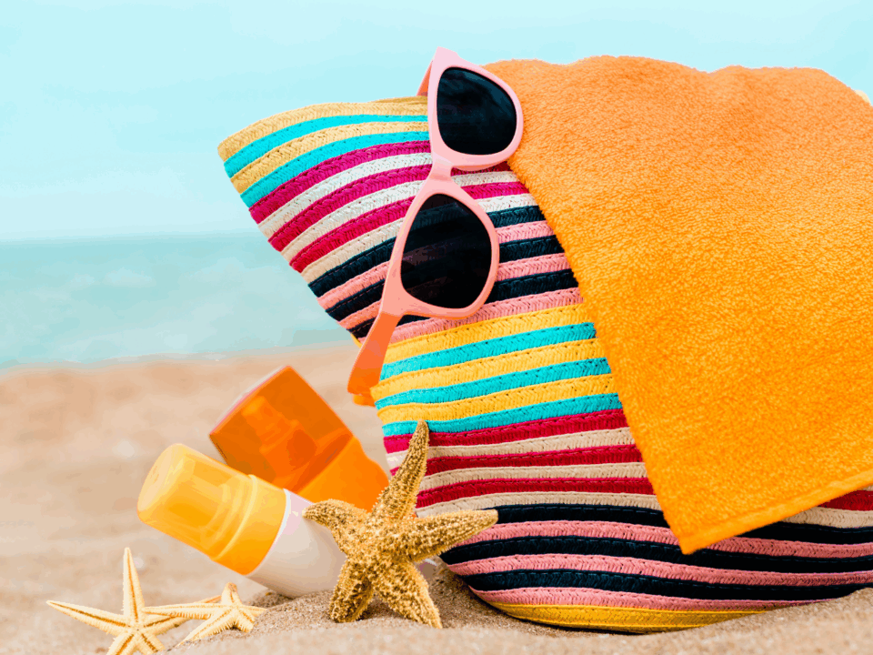 beach bag, sunglasses, and sunscreen on the beach