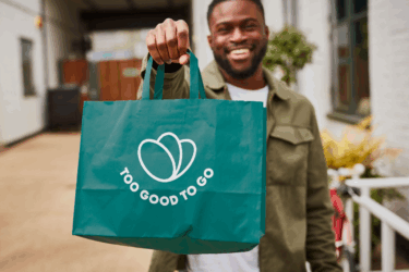 man holding too good to go bag; preventing food waste