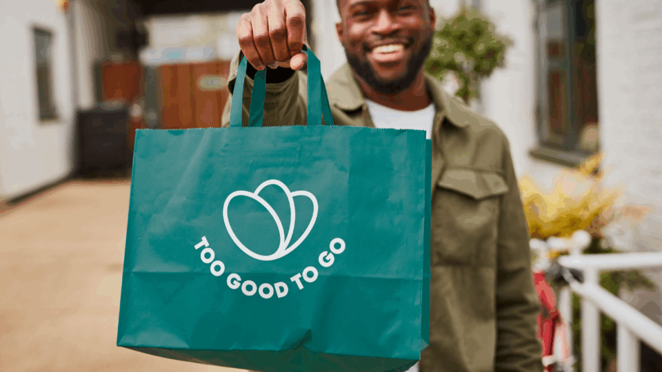 man holding too good to go bag; preventing food waste