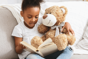 child reading with teddy bear