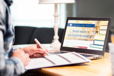 college planning; student sitting at laptop and applying to college