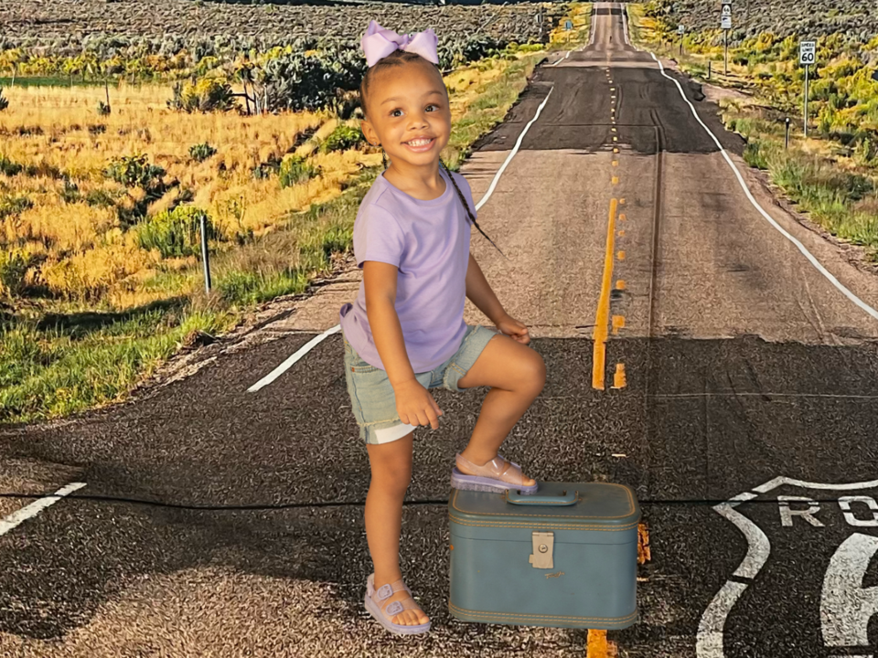 family trips; girl with foot on suitcase on route 66 backdrop