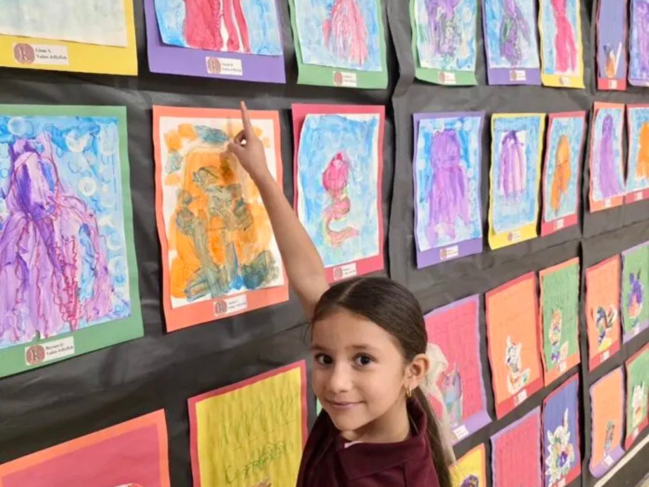 East Baton Rouge Parish Schools; girl pointing to a picture of her artwork