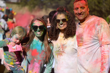 family-friendly events; family covered in colorful powders at Holi Festival