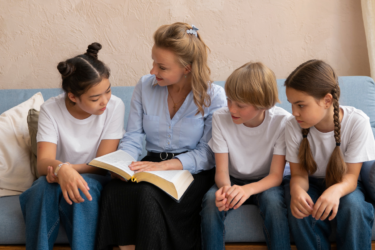 woman and children sitting down reading the Bible; faith