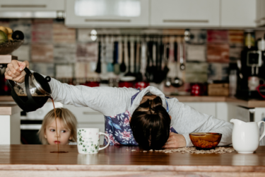 woman pouring coffee onto table instead of cup; head down on the table; child looking on; invisible illness