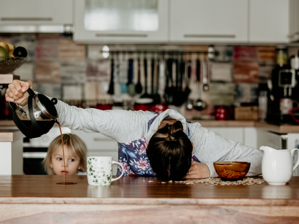 woman pouring coffee onto table instead of cup; head down on the table; child looking on; invisible illness