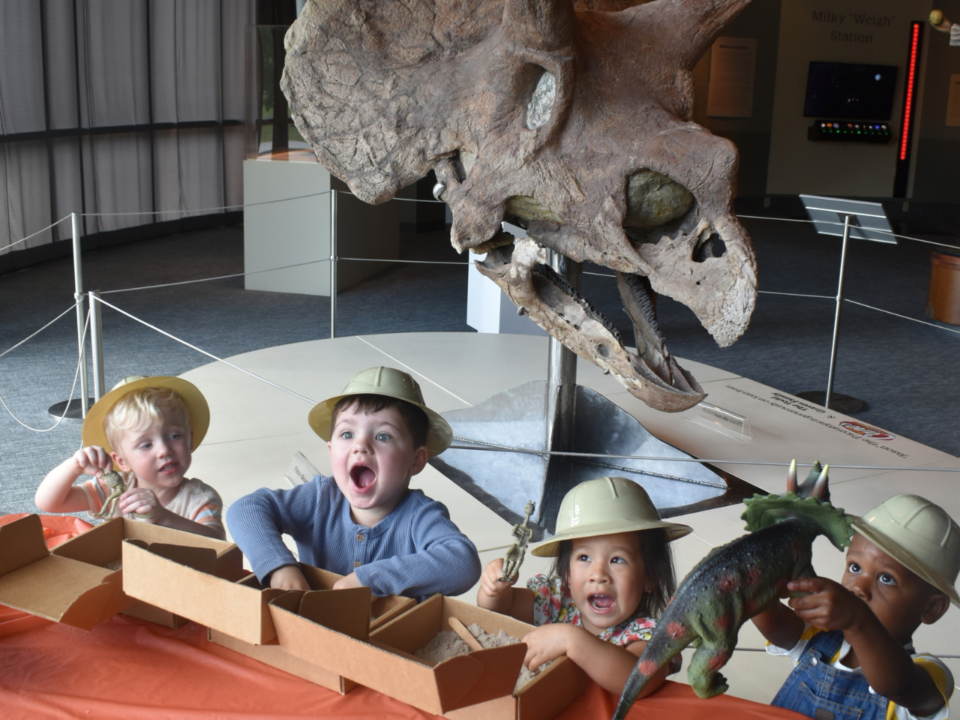 Dino Day at LASM; four children standing in front of “Jason,” a 66-million-year-old Triceratops skull